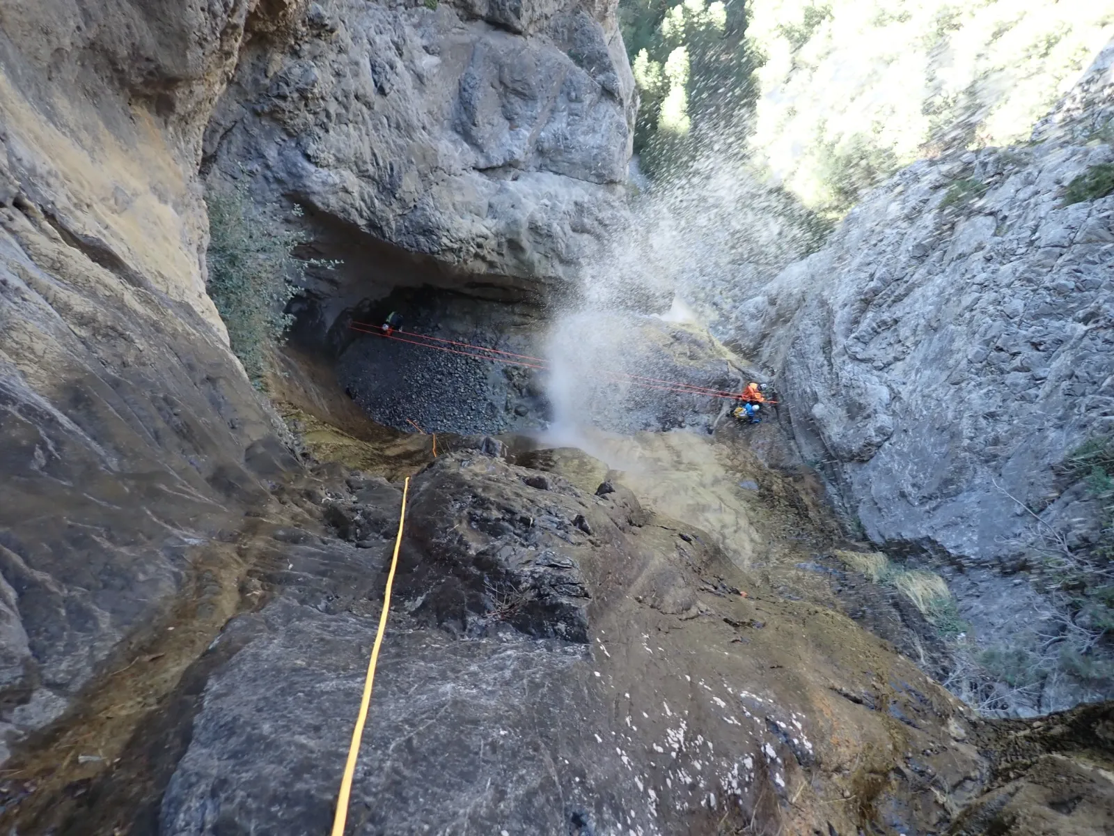 Barranquista en rápel junto a una cascada en un barranco.